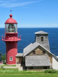 Lighthouse by sea against sky