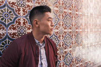 Young man looking away against wall