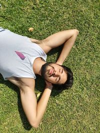 High angle view of young man lying on grassy field