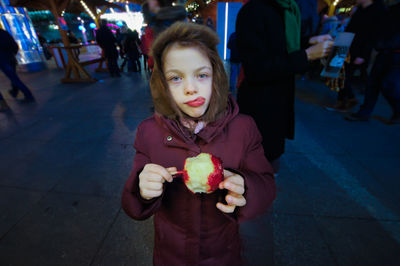 Portrait of girl eating food at night