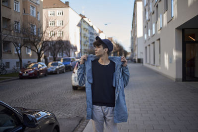 Young man walking on sidewalk in city