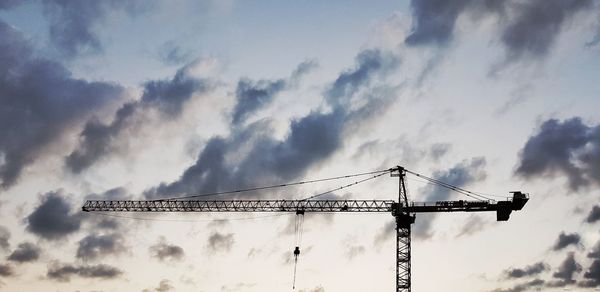 Low angle view of silhouette crane against sky