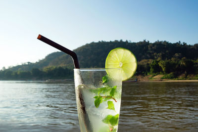 A glass of iced mojito with lime and leaves of mint on a background of river during of laos.