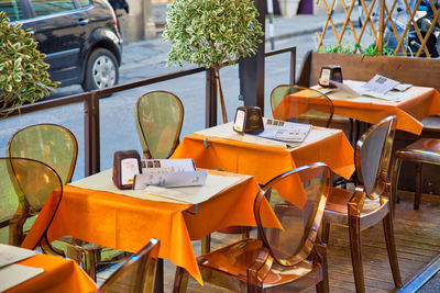 Empty chairs and tables at sidewalk cafe