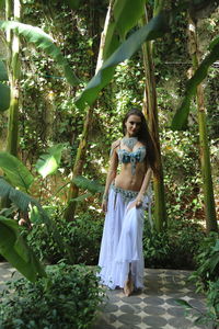 Portrait of beautiful young bellydancer wearing her belly dancing outfit and standing to leaf trees