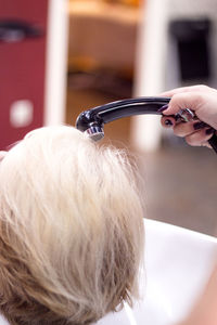 Close-up of hairdresser woman holding dryer over customer head 