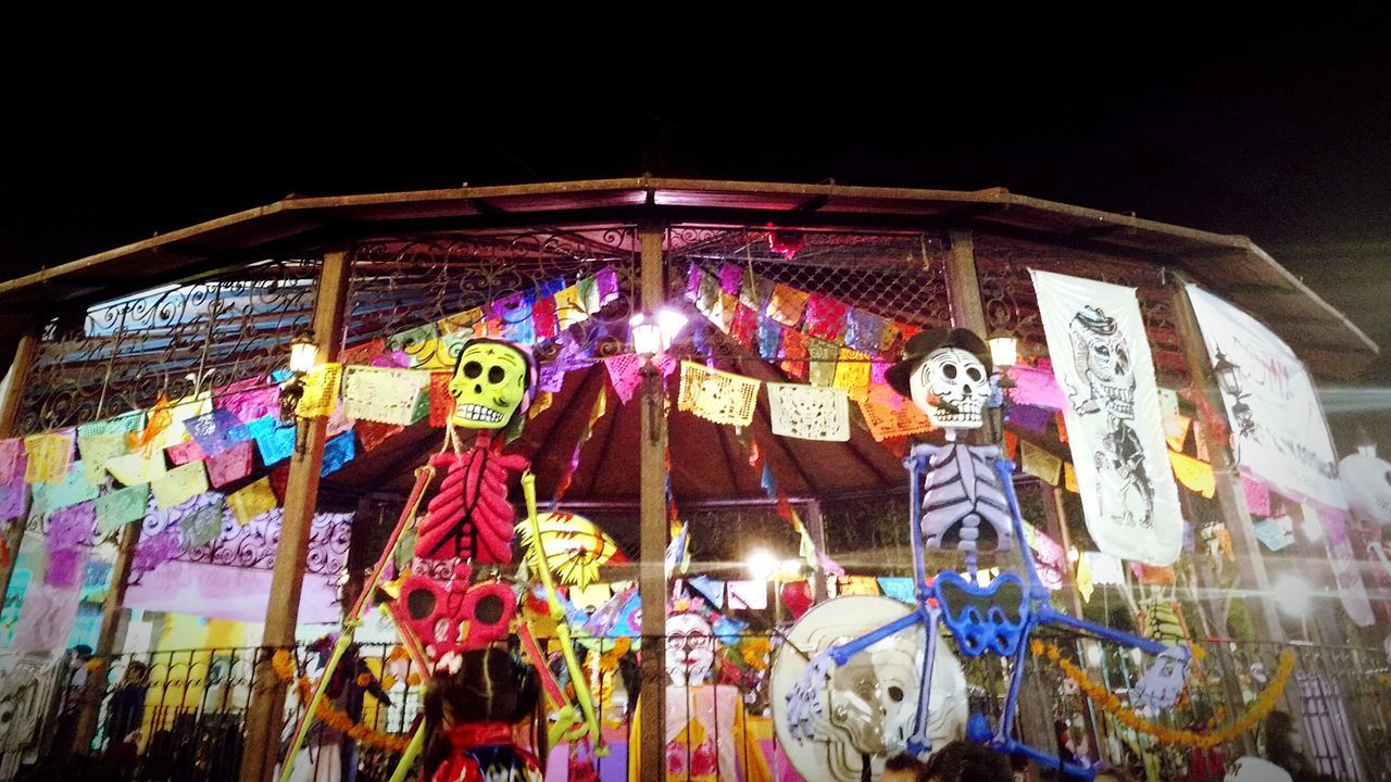 LOW ANGLE VIEW OF ILLUMINATED LANTERNS HANGING ON DISPLAY AT NIGHT