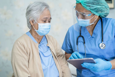 Doctor wearing mask examining senior patient at hospital