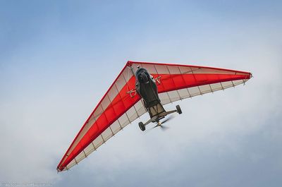 Low angle view of red airplane flying in sky