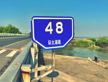 Information sign by road against blue sky