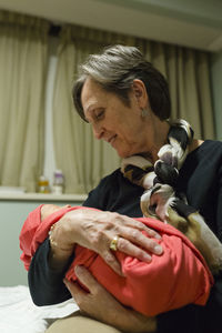 Grandmother looks down lovingly at newborn baby grandchild in hospital