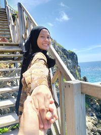 Portrait of smiling young woman by sea against sky