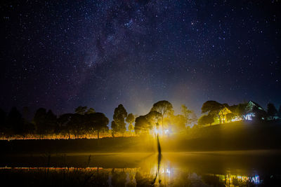 Scenic view of illuminated trees against sky at night