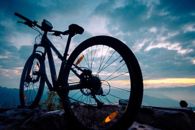 Bicycle by sea against sky during sunset