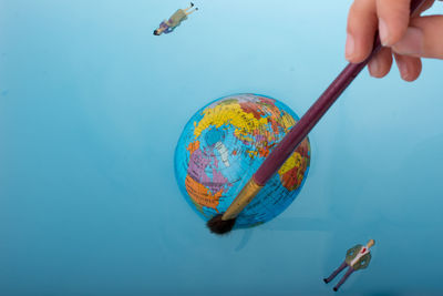 Close-up of person hand painting globe on paper