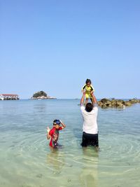 People in sea against clear sky