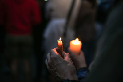 Cropped hands of protestors holding burning candle during protest at night