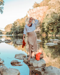 A village young peasant woman in folk slavic clothes washes clothes on a summer day on the river. 