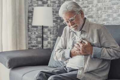 Side view of man using mobile phone while sitting on sofa at home