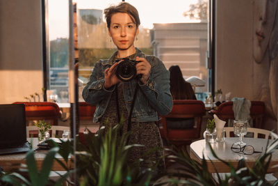 Portrait of young woman photographing with camera