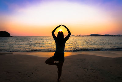 Silhouette person by sea against sky during sunset