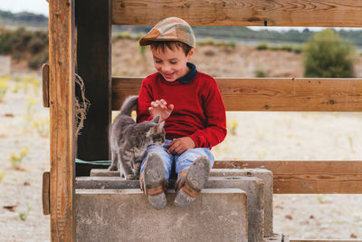 Cute smiling boy playing with cat outdoors
