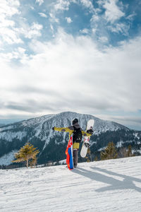 Full length of woman skiing on snow covered mountain against sky