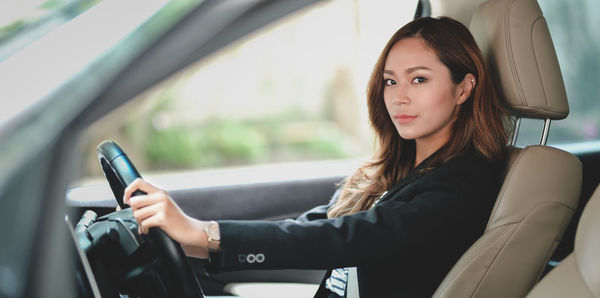 Portrait of woman sitting in car seen through window