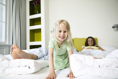 Portrait of smiling little girl on hotel bed with her parents