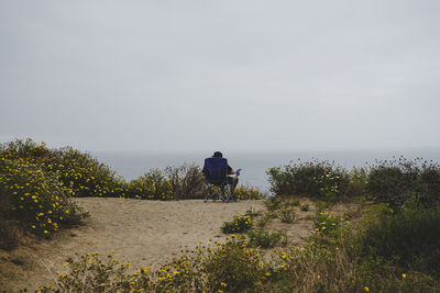 Rear view of man riding by sea against sky