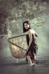 Portrait of young woman fishing in river