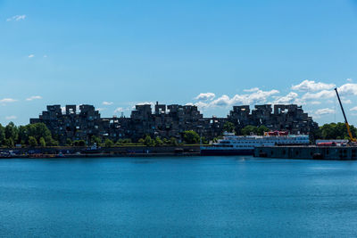 Sea by buildings against blue sky