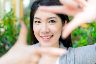 Portrait of smiling young woman making finger frame