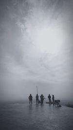 Silhouette people on sea against sky