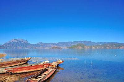 Fishing boat in lake against clear blue sky