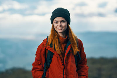 Portrait of beautiful young woman standing against sky during winter