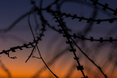 Low angle view of barbed wire fence against sky