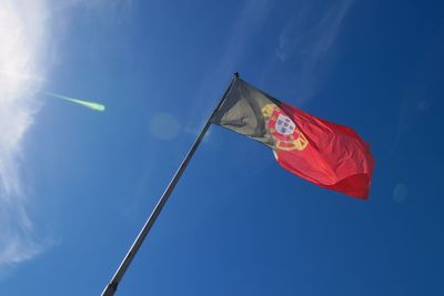 Low angle view of portuguese flag against blue sky