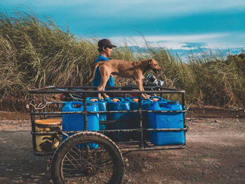 Side view of man riding motorcycle with dog on cart
