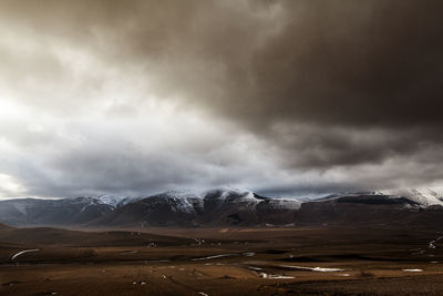 Scenic view of landscape against storm clouds