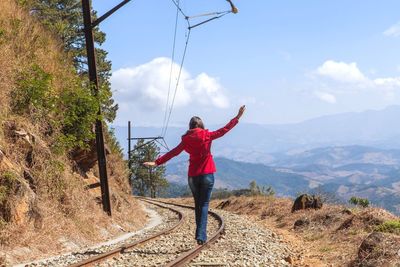 Rear view of woman balancing on railroad track