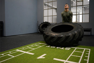 Young man exercising with tire in gym