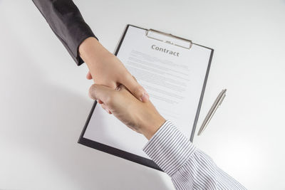 Close-up of hand holding book against white background