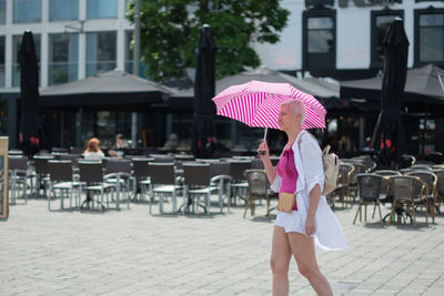 Middle-aged woman with a short haircut with an umbrella protecting from sun