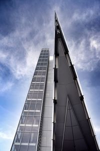 Low angle view of skyscrapers against cloudy sky