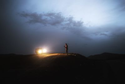 Man standing on landscape against sky at night