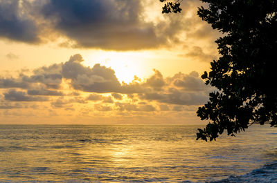 Scenic view of sea against cloudy sky at sunset