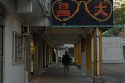 Rear view of man walking on footpath amidst buildings