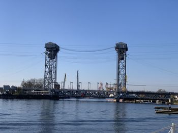 Electricity pylon by river against sky