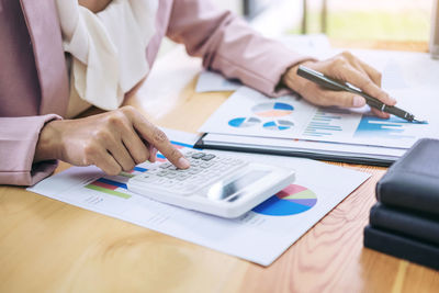 Midsection of businesswoman using calculator in office